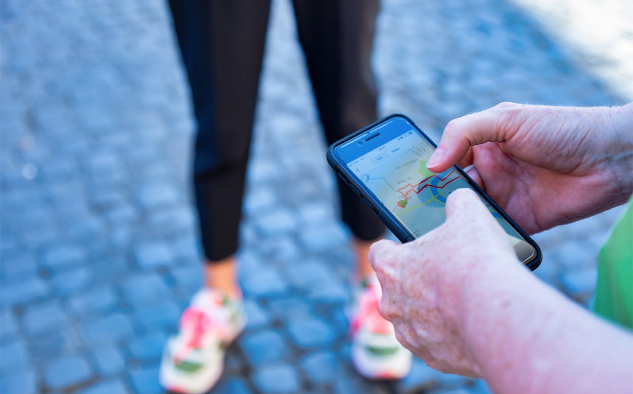 Person using a smartphone map app on a cobblestone street in Venice.