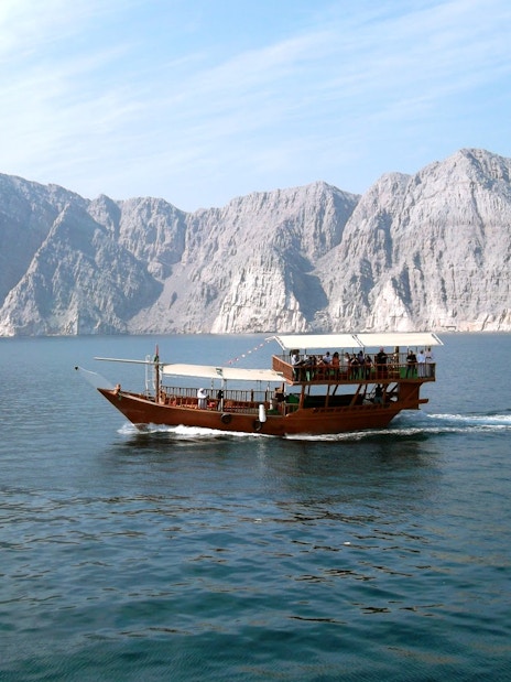 Dhow cruise on Musandam Dibba waters with rocky mountains in the background.