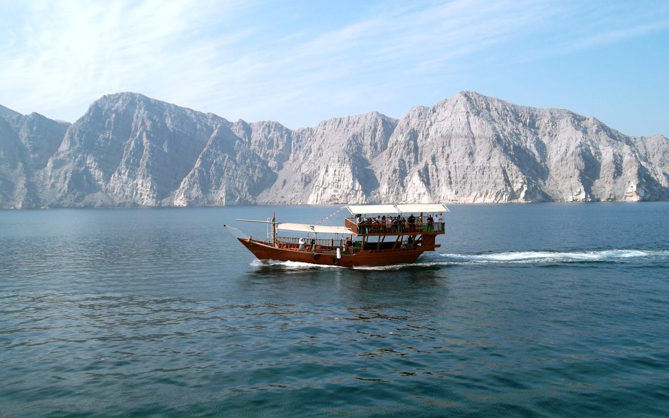 Dhow cruise on Musandam Dibba waters with rocky mountains in the background.