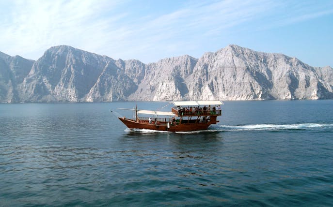 Dhow cruise on Musandam Dibba waters with rocky mountains in the background.