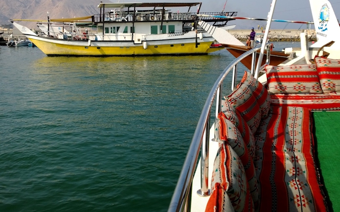 Dhow boat with colorful seating on Musandam Dibba tour, Oman.