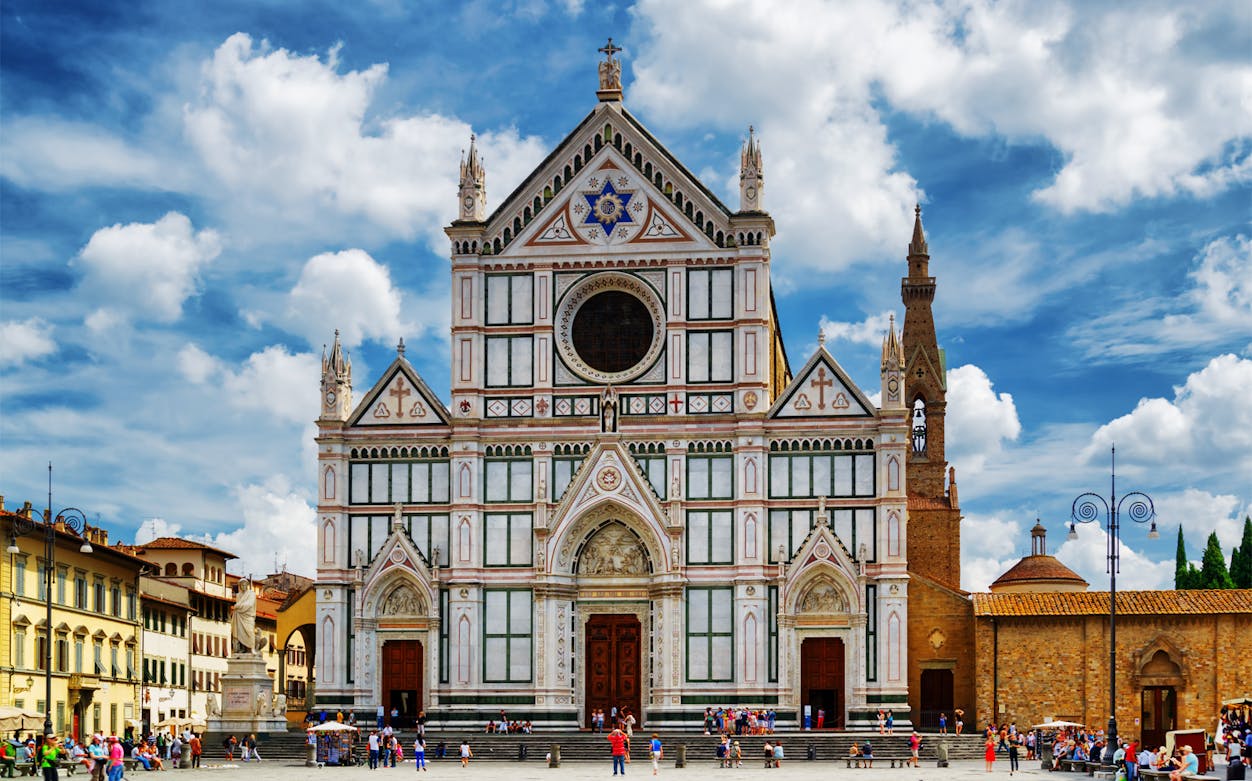 Santa Croce Basilica facade in Florence, Italy, with tourists exploring the square.