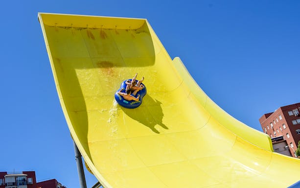 Visitors on a yellow water slide at Guadalpark Sevilla.