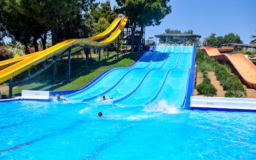 Water slides at Guadalpark Sevilla with people splashing into the pool.