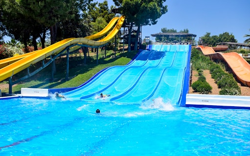 Water slides at Guadalpark Sevilla with people splashing into the pool.