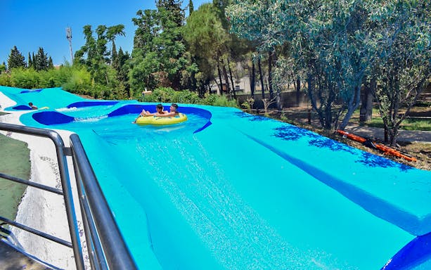 Visitors enjoying a water slide at Guadalpark Sevilla.