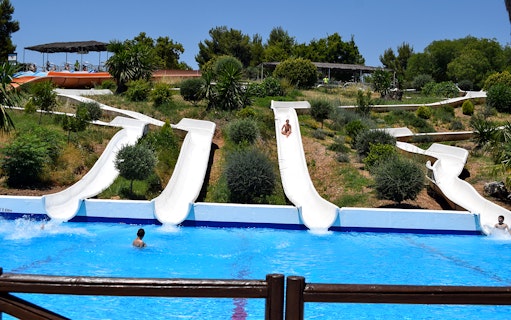 Water slides at Guadalpark Sevilla with people splashing into the pool.