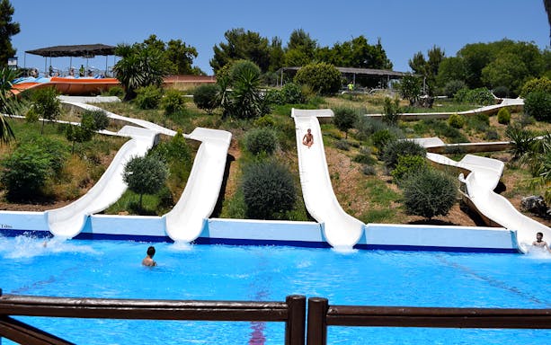 Water slides at Guadalpark Sevilla with people splashing into the pool.
