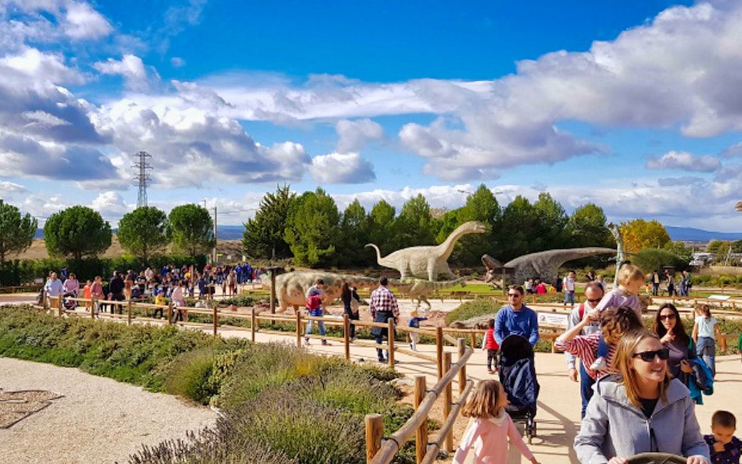 Visitors walking among dinosaur sculptures at Dinópolis Teruel, Spain.