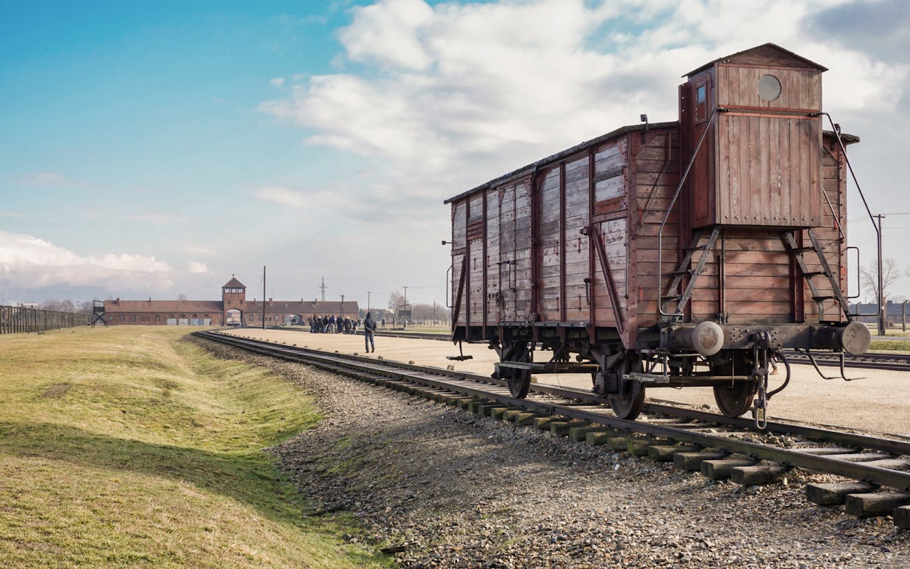 Railway car at Auschwitz Birkenau with distant view of entrance gate, Poland.