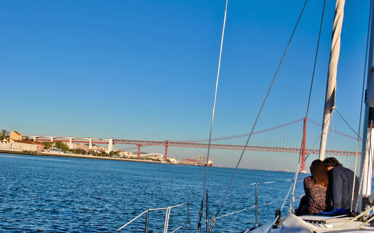 Couple sailing near Lisbon's 25 de Abril Bridge on a private cruise.