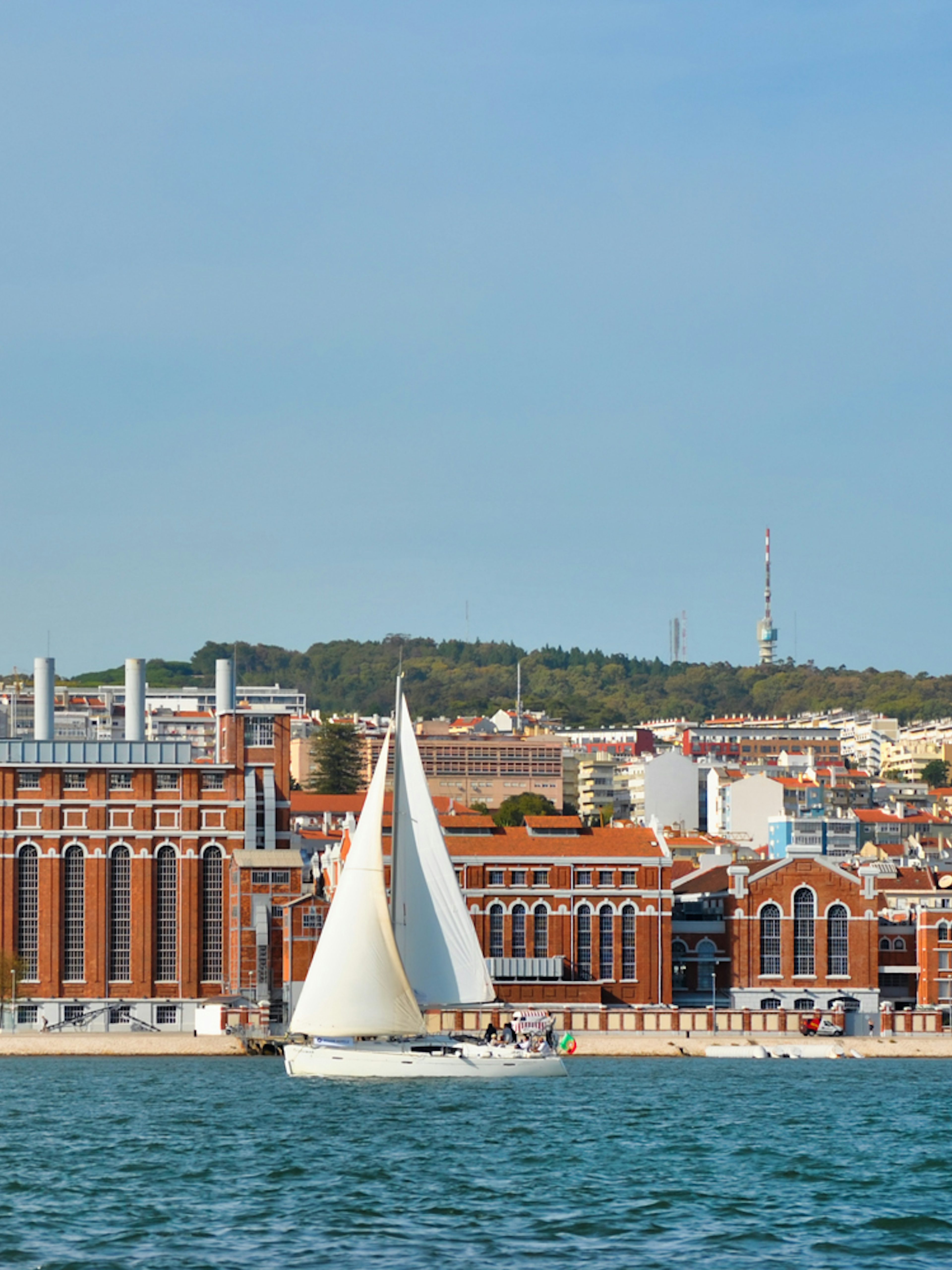 Sailboats on Tagus River with Lisbon cityscape in the background.
