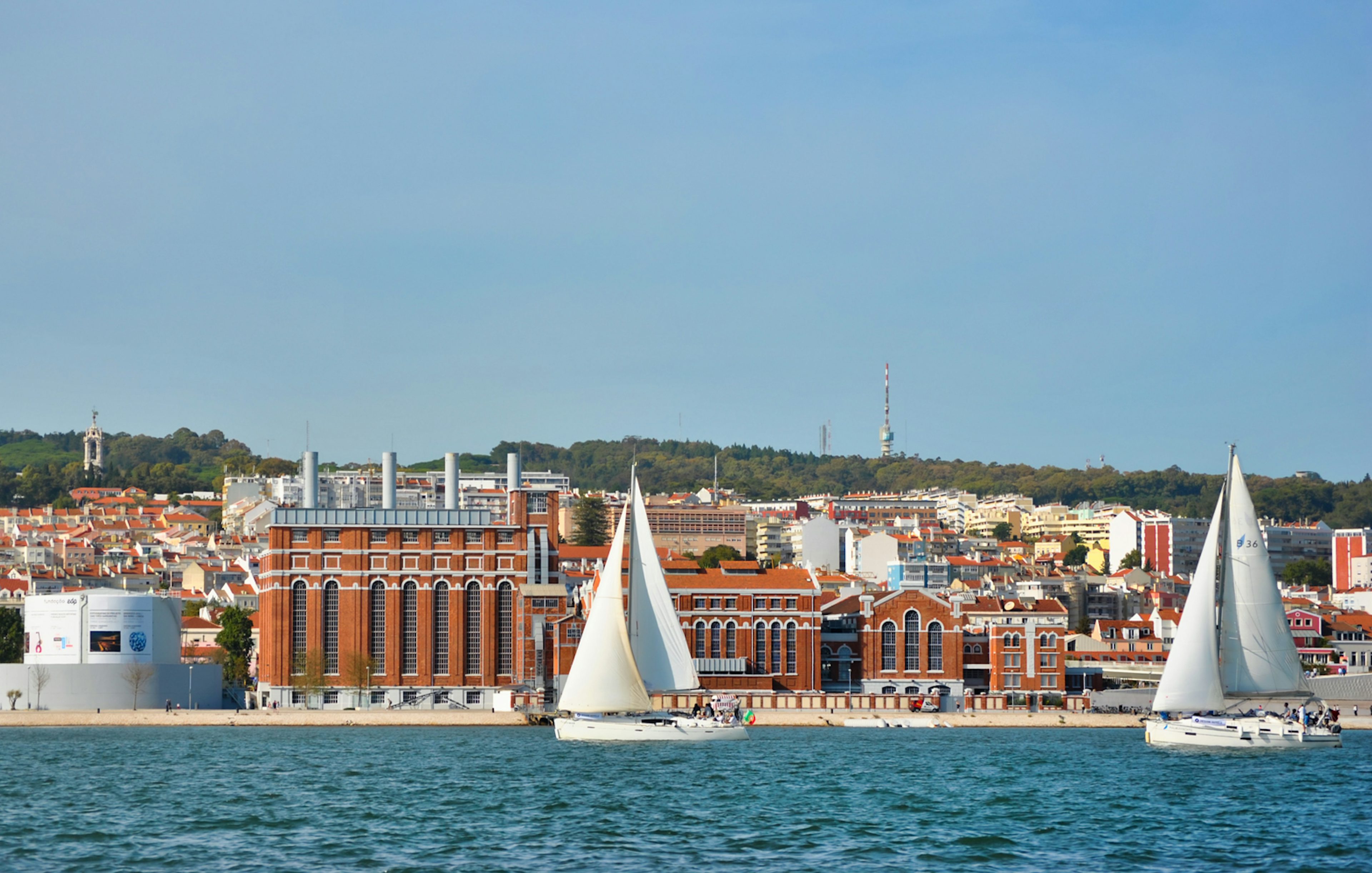 Sailboats on Tagus River with Lisbon cityscape in the background.