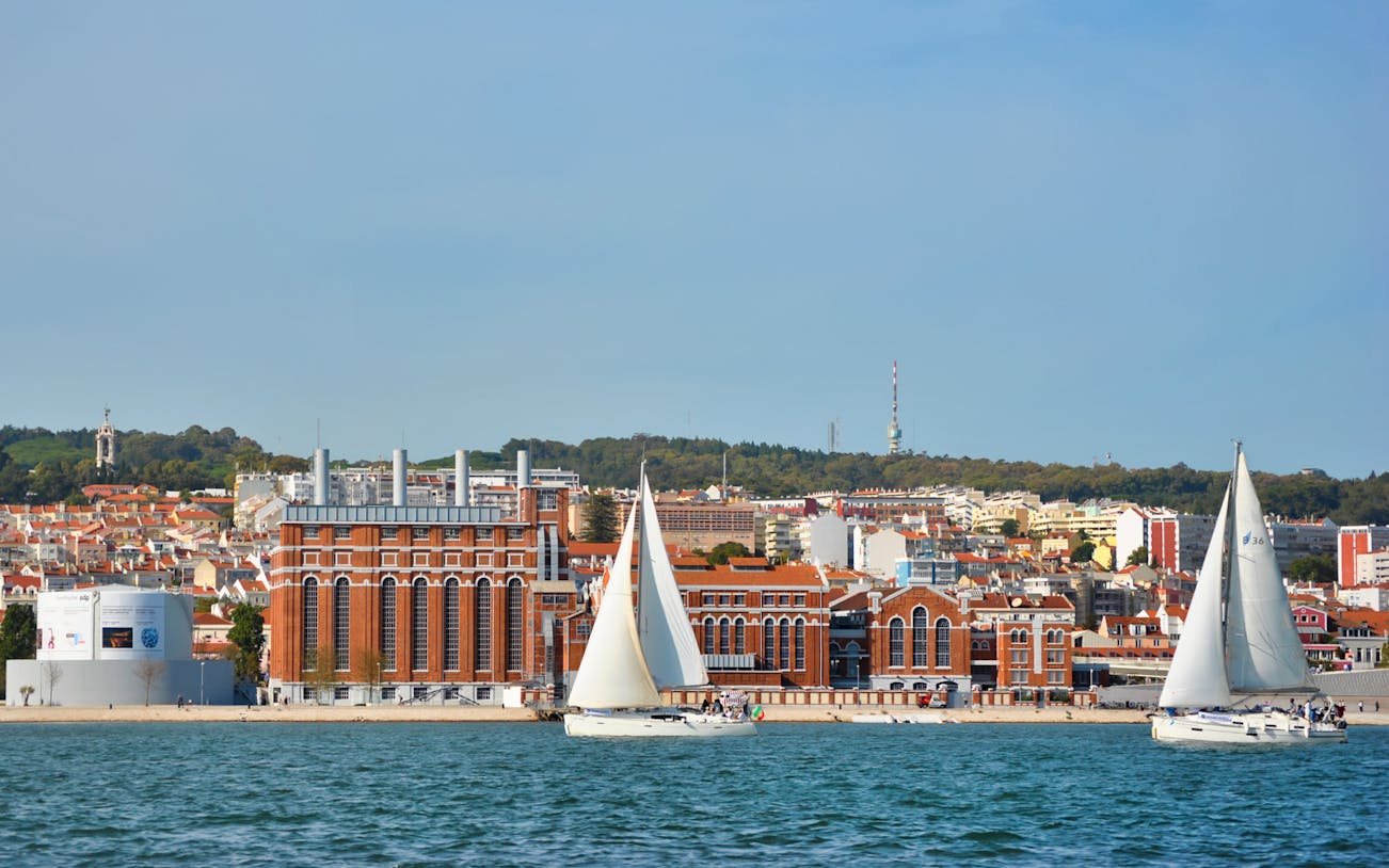 Sailboats on Tagus River with Lisbon cityscape in the background.