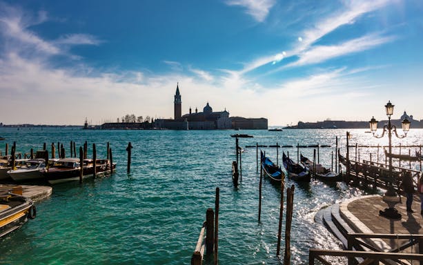 Venice canal view with gondolas and San Giorgio Maggiore in the background.