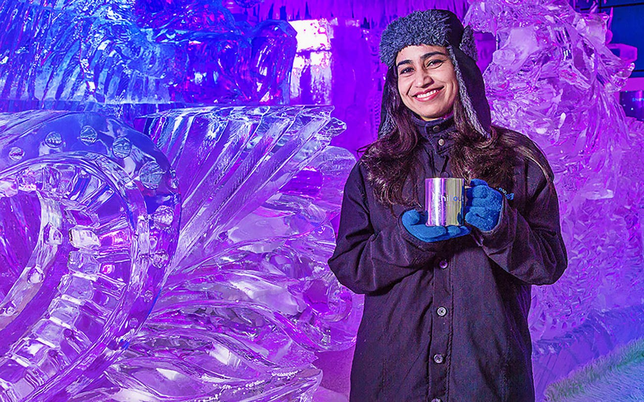 Person enjoying Chillout Ice Lounge Dubai with ice sculptures.