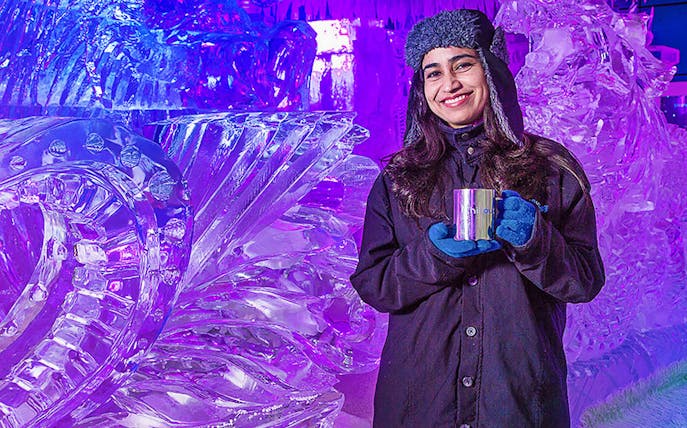 Person enjoying Chillout Ice Lounge Dubai with ice sculptures.