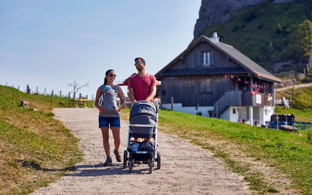 Couple with baby walking near a chalet on Mount Rigi trail.