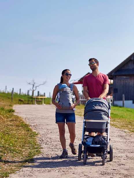 Couple walking with stroller near a chalet on Mount Rigi trail, Switzerland.