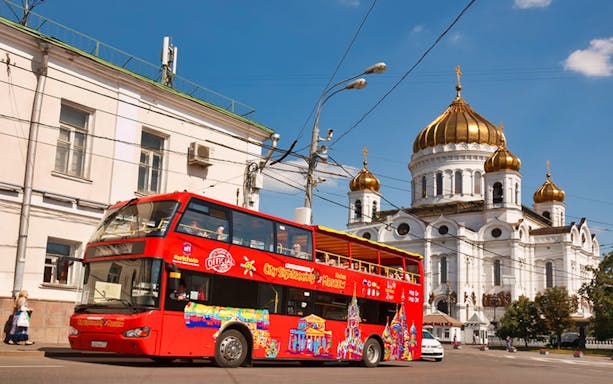 Red double-decker tour bus near Cathedral of Christ the Saviour, Moscow CityPass options.