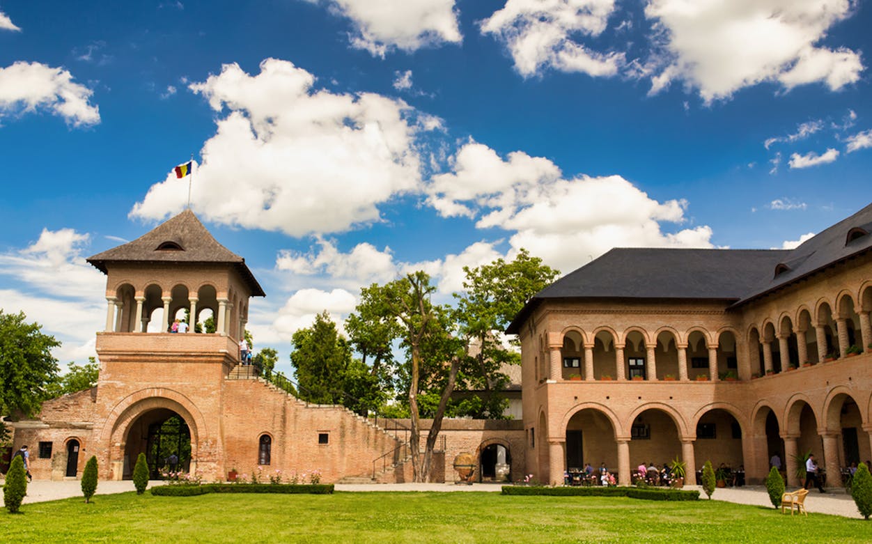 Mogosoaia Palace courtyard with arched brick architecture under a blue sky.