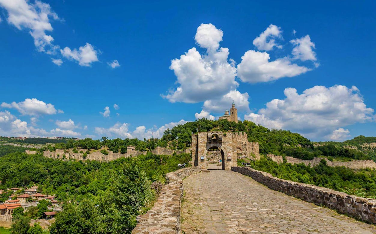 Tsarevets Fortress in Veliko Tarnovo, Bulgaria, with stone walls and lush greenery.