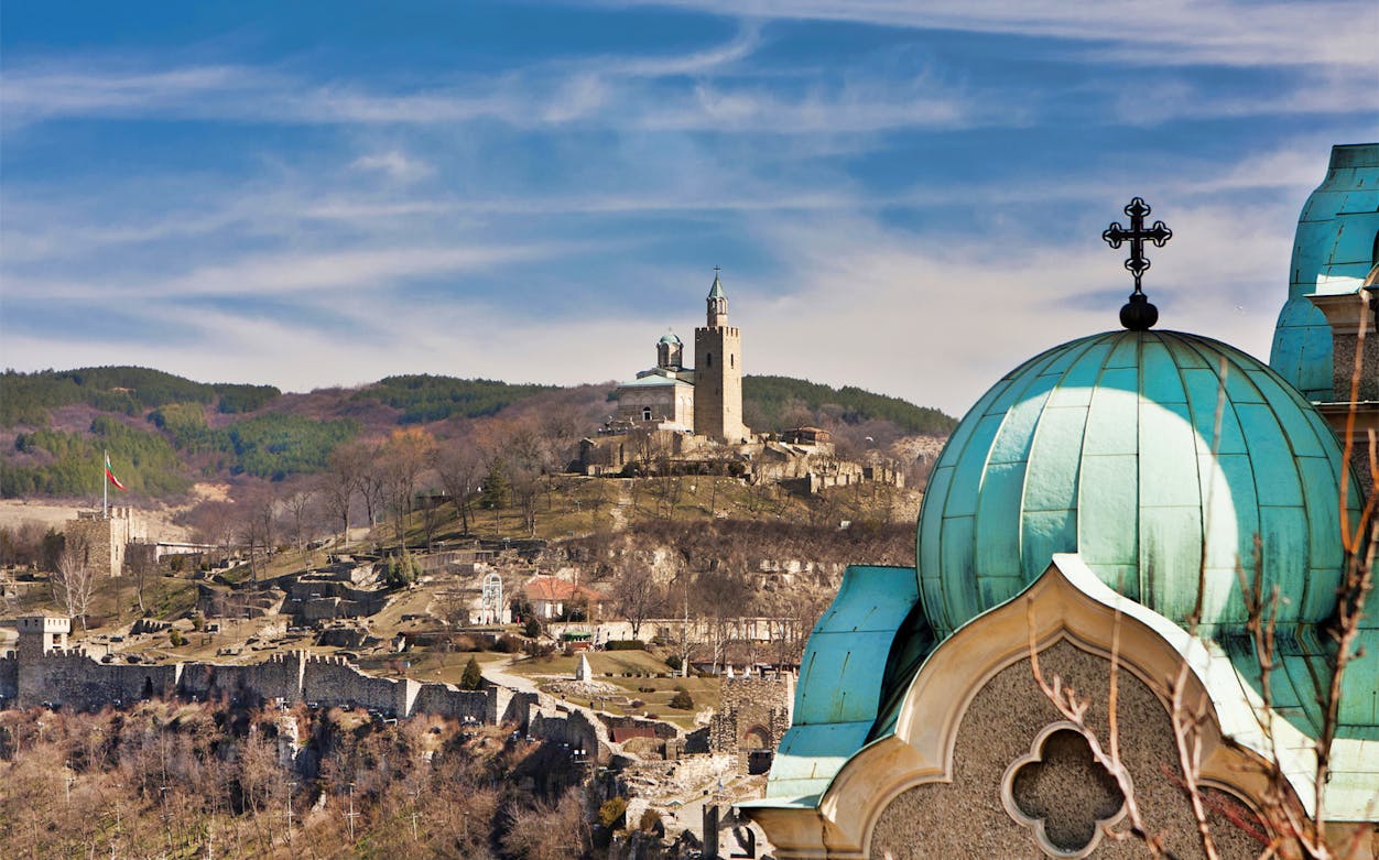 Tsarevets Fortress in Veliko Tarnovo, Bulgaria, with church domes in the foreground.