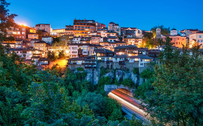 Veliko Tarnovo hillside view at dusk with illuminated buildings, Bulgaria.
