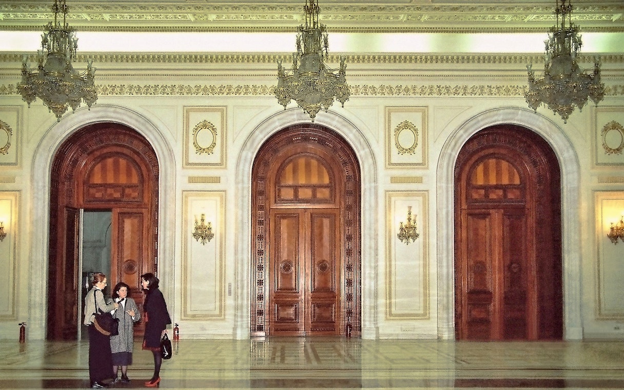 Palace of Parliament interior with ornate doors and chandeliers during guided tour.