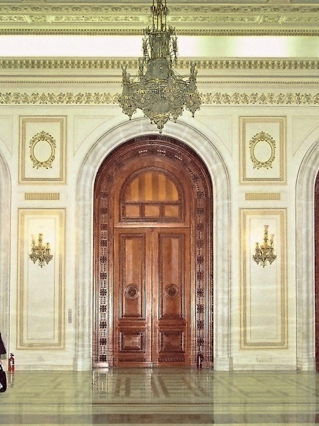 Palace of Parliament interior with ornate doors and chandeliers during guided tour.