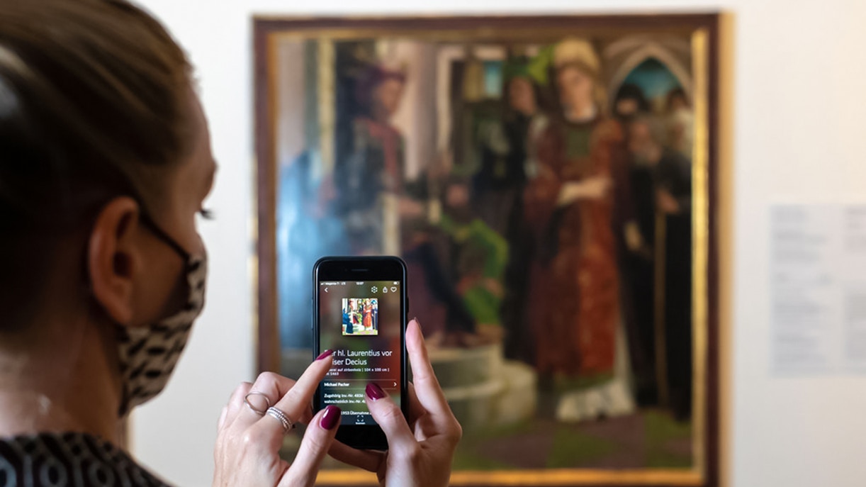Visitor using a smartphone to view art details at Belvedere Palace, Vienna.