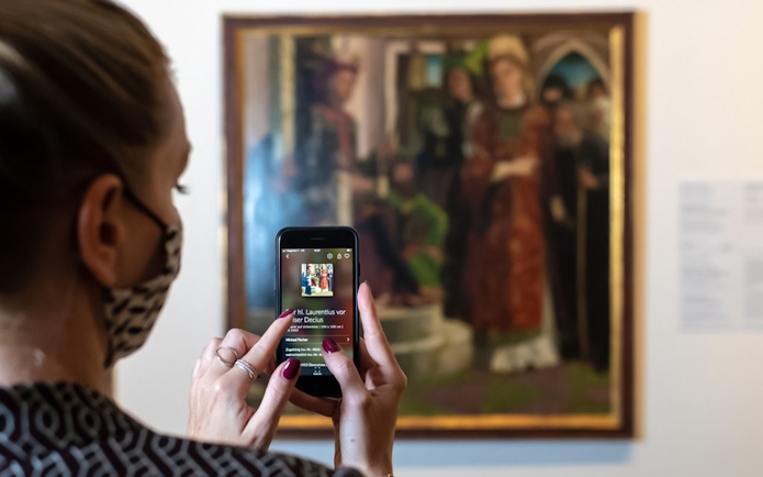 Visitor using a smartphone to view art details at Belvedere Palace, Vienna.