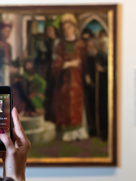 Visitor using a smartphone to view art details at Belvedere Palace, Vienna.