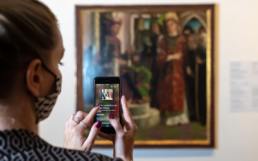 Visitor using a smartphone to view art details at Belvedere Palace, Vienna.