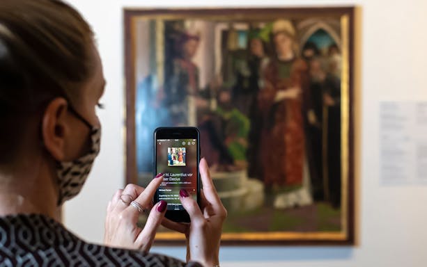 Visitor using a smartphone to view art details at Belvedere Palace, Vienna.