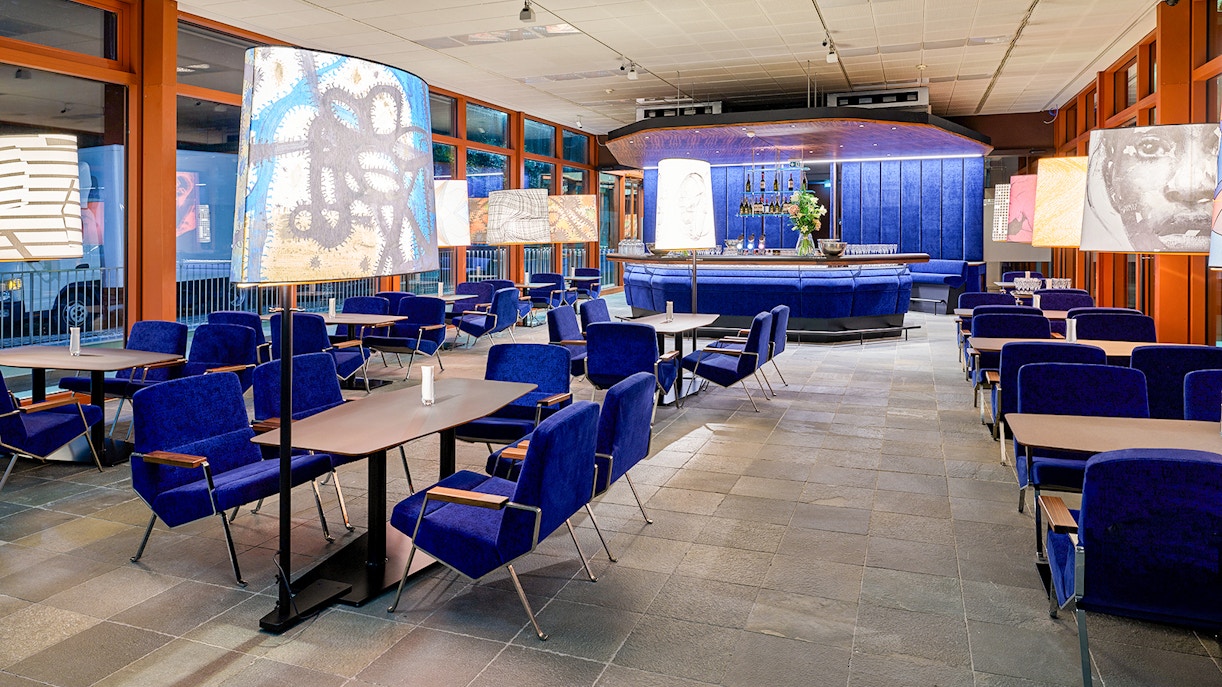 Contemporary art-themed café interior at Belvedere 21, Vienna, with blue seating and artistic lamps.