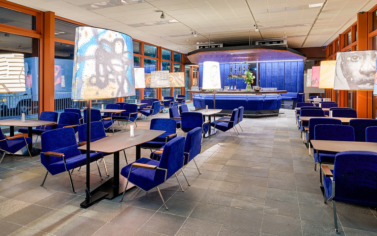 Contemporary art-themed café interior at Belvedere 21, Vienna, with blue seating and artistic lamps.