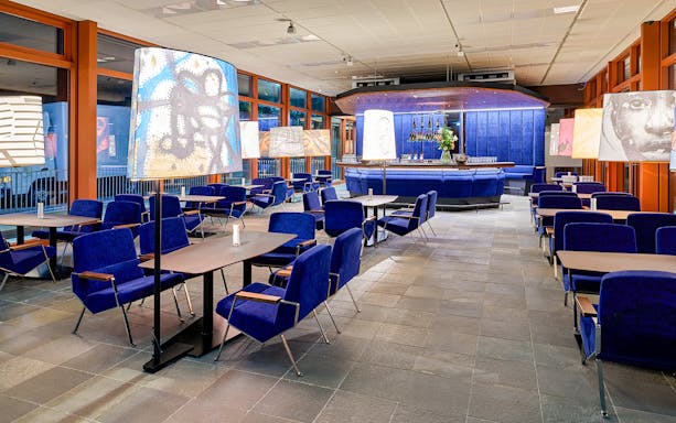 Contemporary art-themed café interior at Belvedere 21, Vienna, with blue seating and artistic lamps.