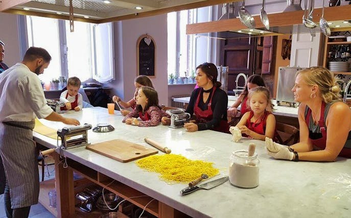 Small group learning pasta making with a chef in a kitchen setting.
