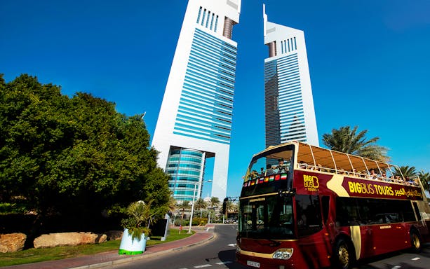 Hop-on hop-off bus in front of Dubai's Emirates Towers.