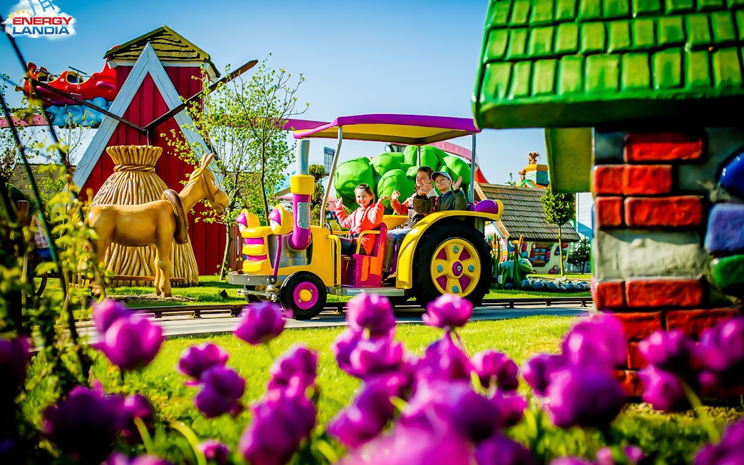 Children riding a colorful tractor ride at Energylandia Amusement Park.