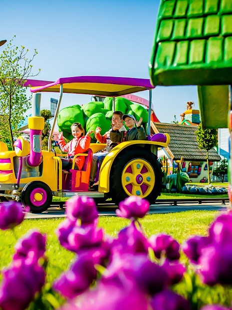 Children riding a colorful tractor ride at Energylandia Amusement Park.