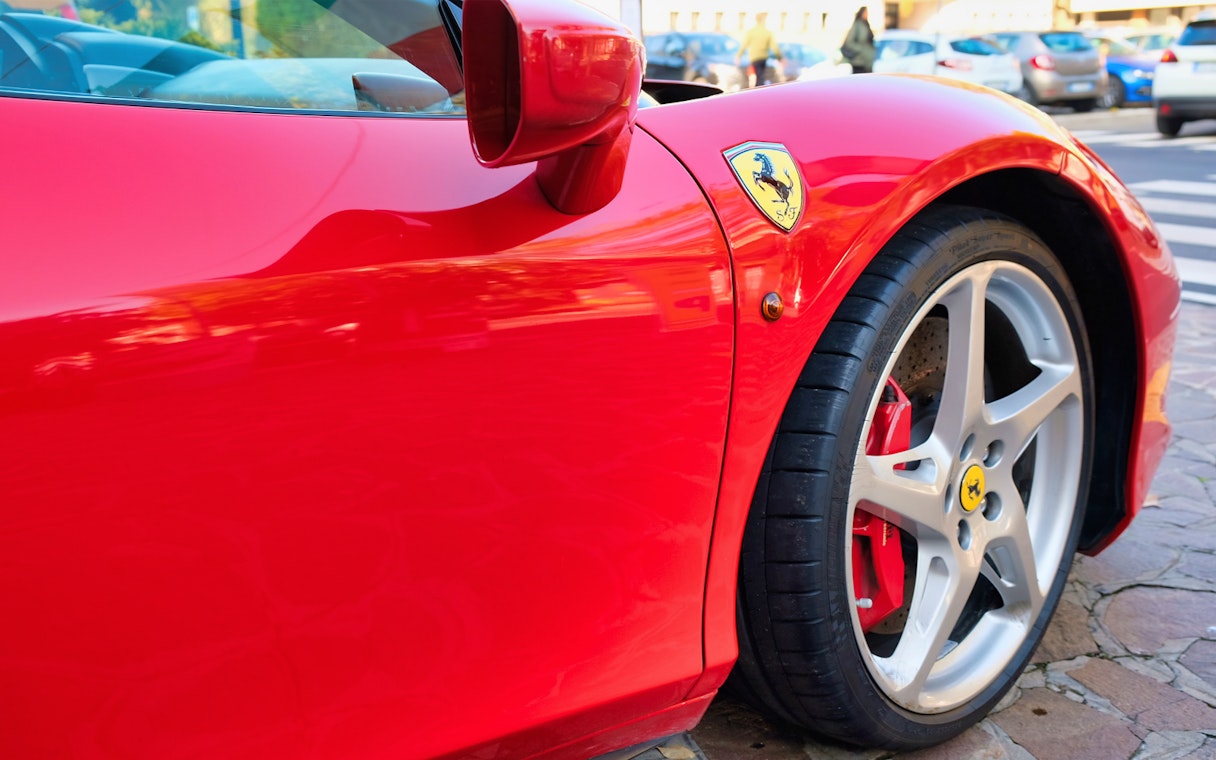 Ferrari 458 Italia close-up in Maranello, showcasing wheel and emblem.