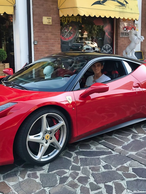 Test driving a red Ferrari 458 Italia on a cobblestone street in Maranello.