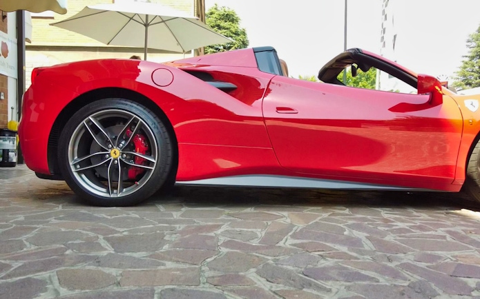 Ferrari 488 Spider parked on cobblestone street, ready for test drive experience.
