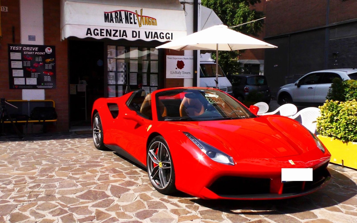 Ferrari 488 Spider parked outside travel agency in Maranello, Italy.