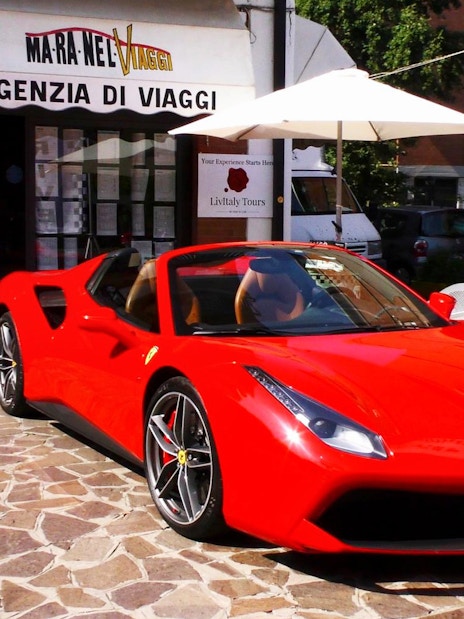 Ferrari 488 Spider parked outside travel agency in Maranello, Italy.