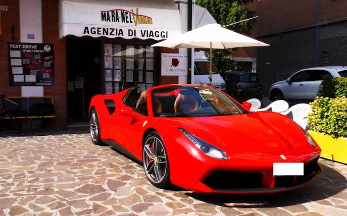 Ferrari 488 Spider parked outside travel agency in Maranello, Italy.