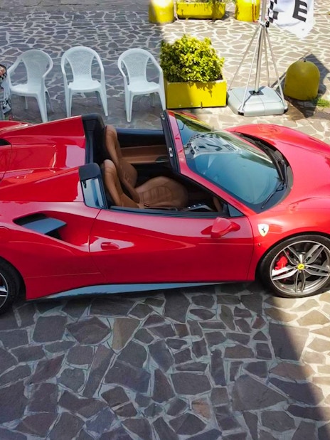 Red Ferrari 488 Spider parked on stone pavement, ready for test drive experience.