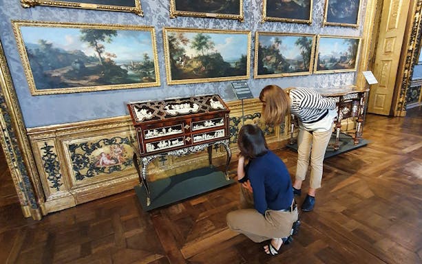 Visitors examining ornate furniture and paintings at Palazzo Madama, Turin.